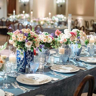 Elegant table setting with floral centerpieces and candlelight in a formal dining room.