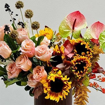 Bouquet of flowers with sunflowers, roses, and anthuriums on a light gray background
