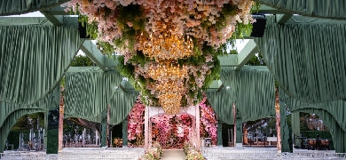 Floral archway with white flowers and greenery leading to a scenic landscape.