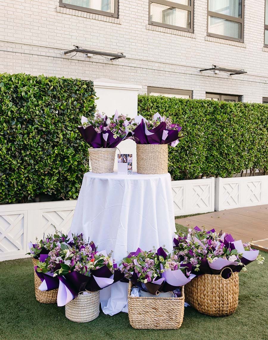 Bouquets of flowers in woven baskets on a table outdoors.