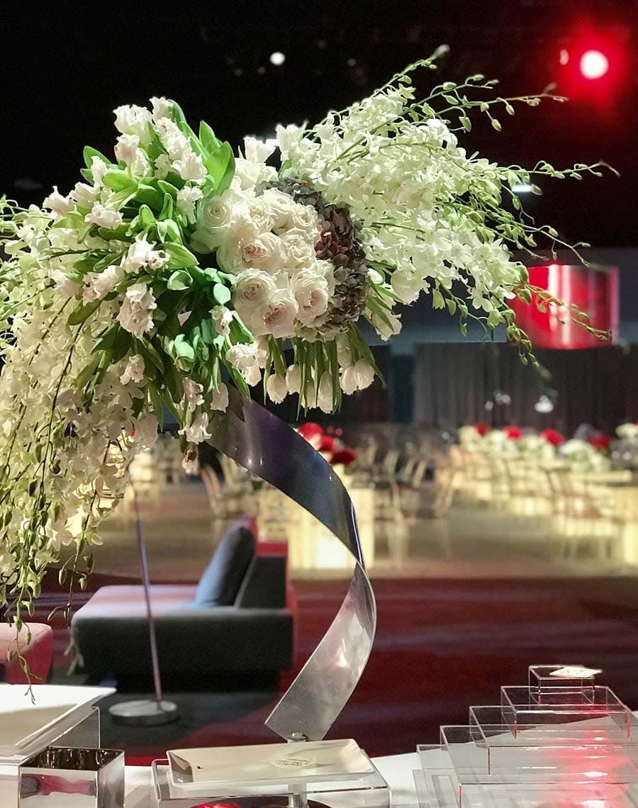 Decorative floral arrangement on a table with a blurred event background