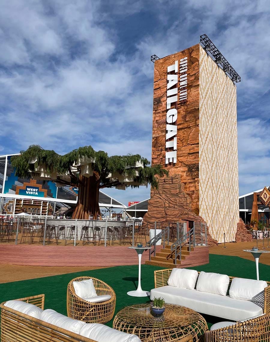 Tailgate-themed outdoor area with wooden tower, seating, and sports stadium in the background.