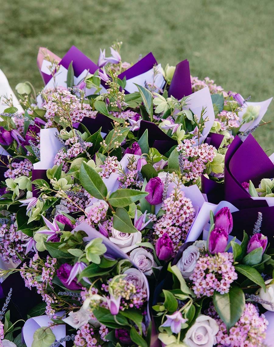 Bouquet of purple and green flowers with ribbons on a blurred green background