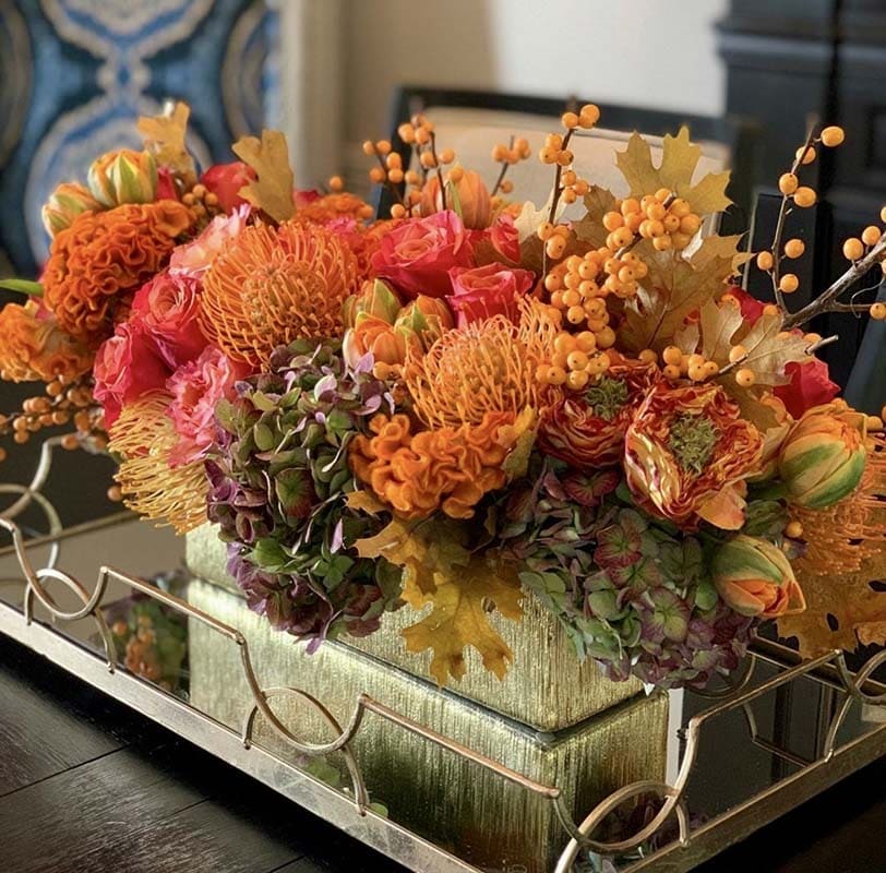 Colorful floral arrangement on a reflective surface with a blurred background