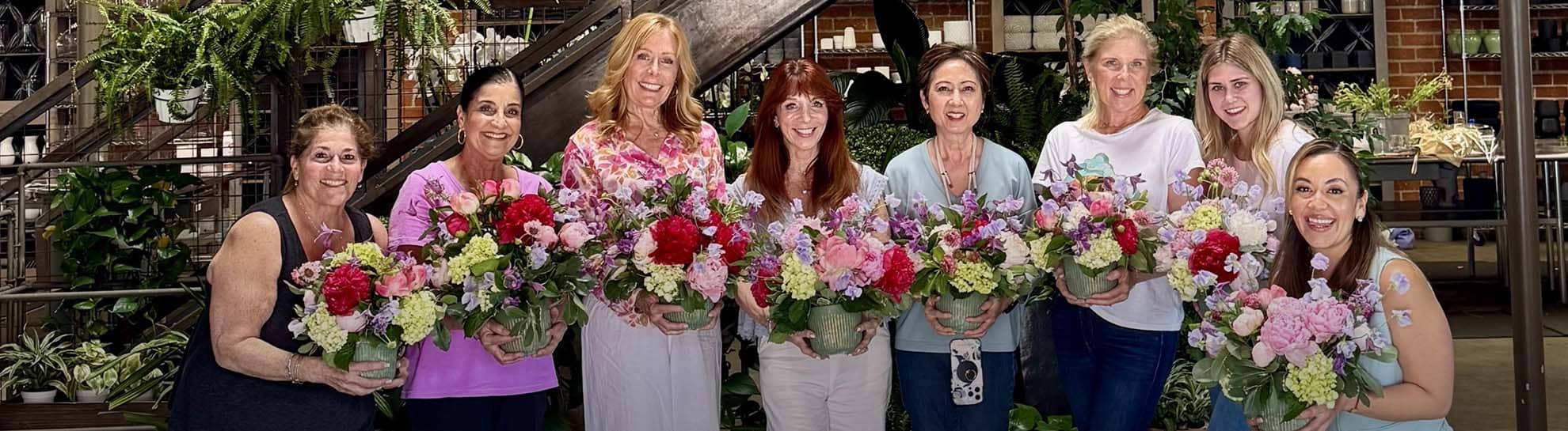 Group of women holding flower bouquets in a store setting