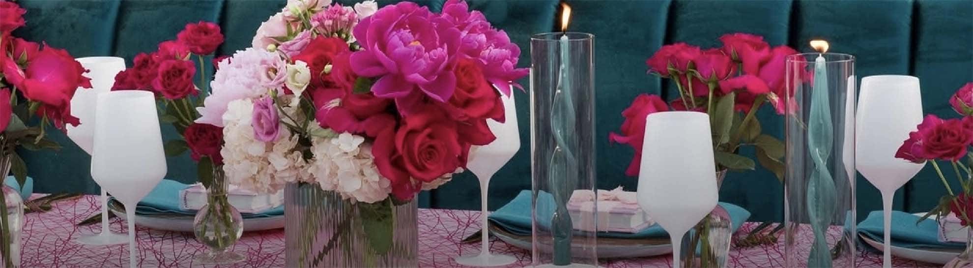 Decorative setup with flowers, candles, and white chairs against a teal background
