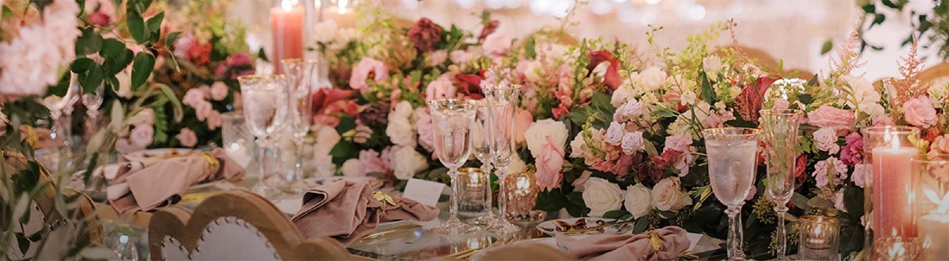 Decorative table setting with flowers, candles, and glasses on a festive background