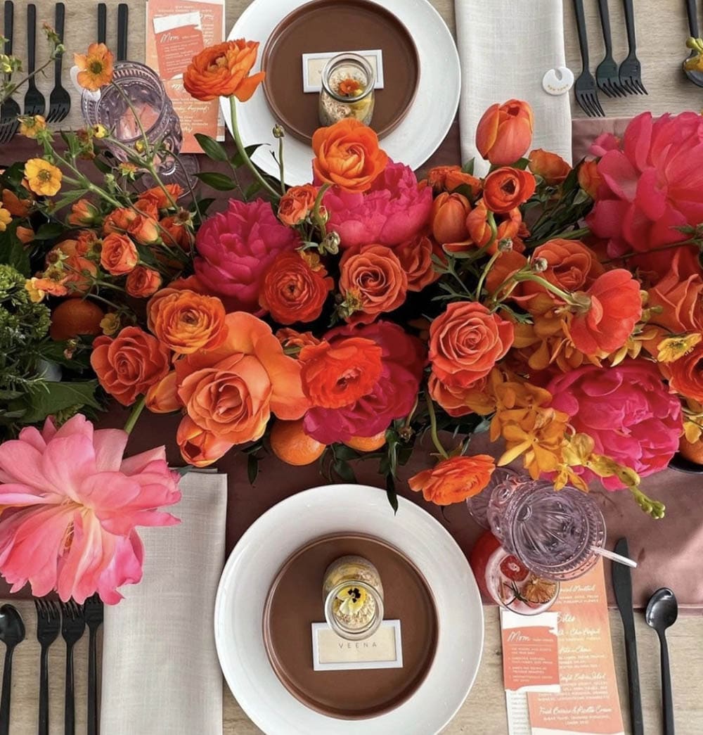 Decorative table setting with colorful flowers, plates, and cutlery.