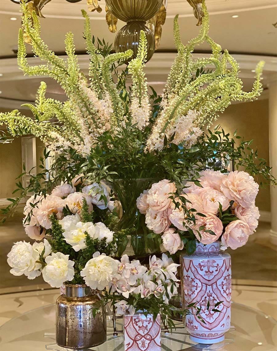 Decorative floral arrangement with vases on a reflective surface, possibly in a hotel lobby.