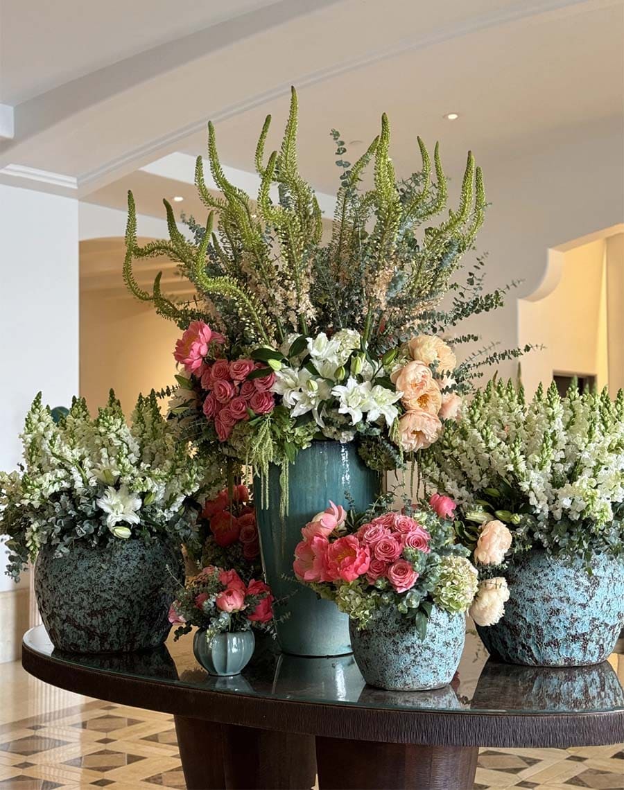 Decorative floral arrangements in various vases on a table indoors.