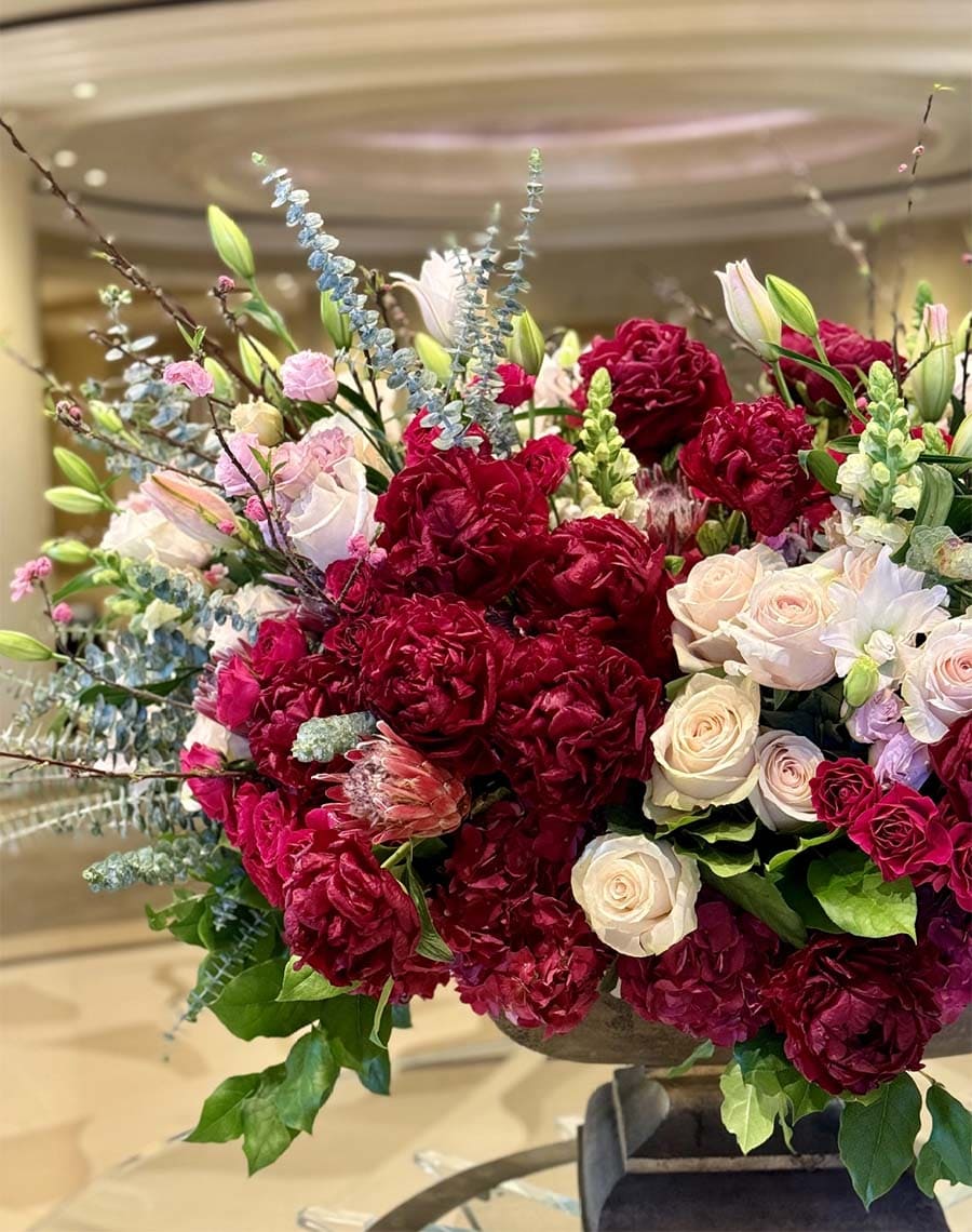 Bouquet of red and pink flowers with greenery in a vase.