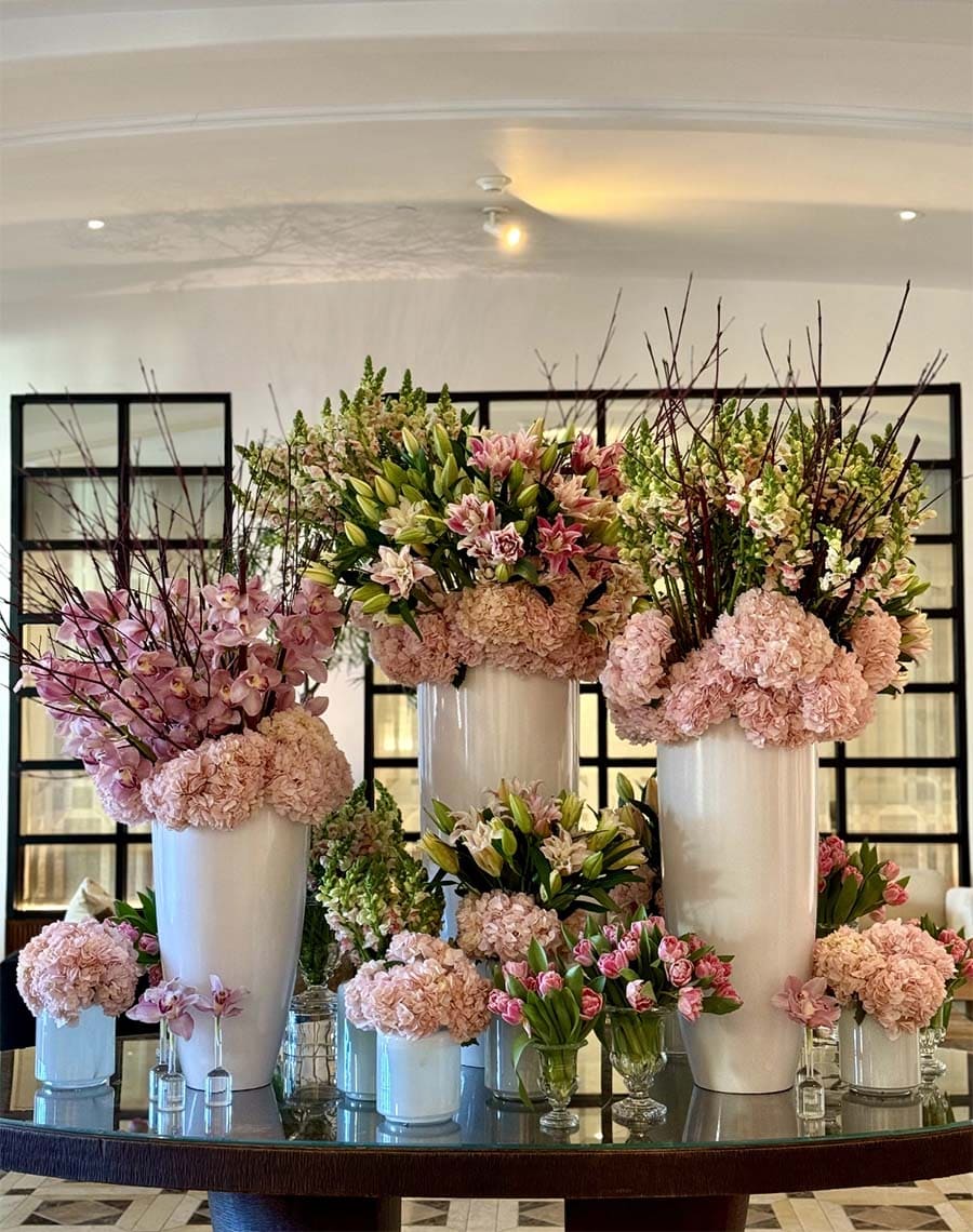 Table with various floral arrangements in vases against a neutral background