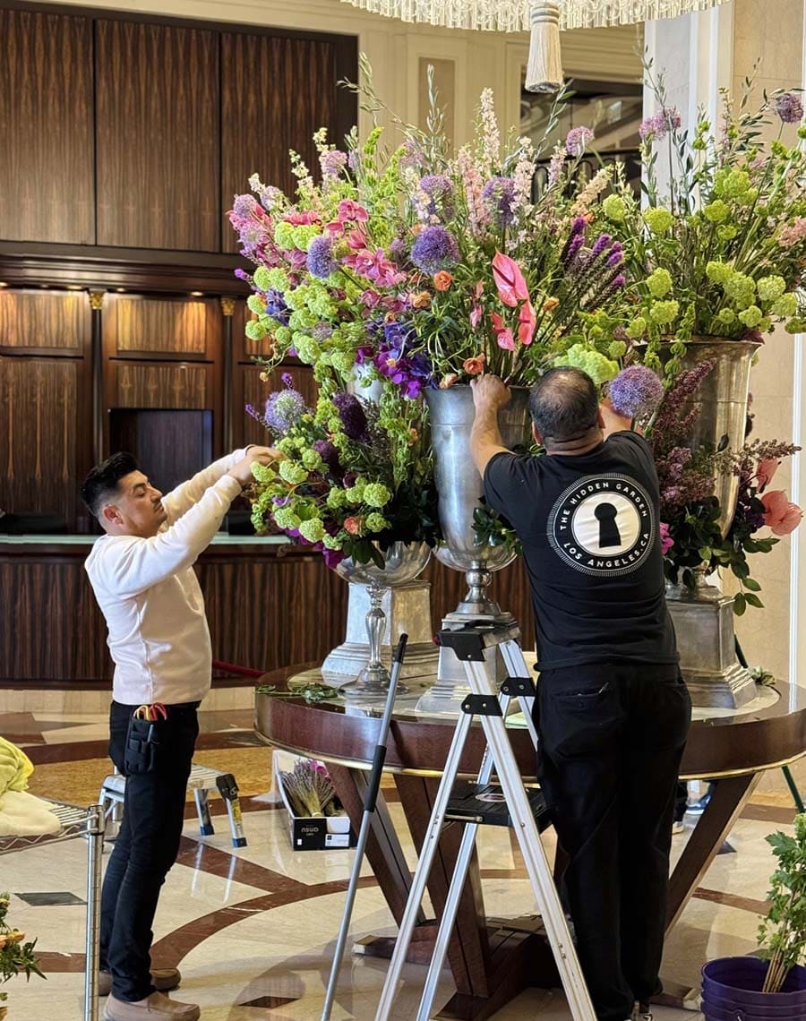 Two floral decorators arranging flowers in a hotel lobby.