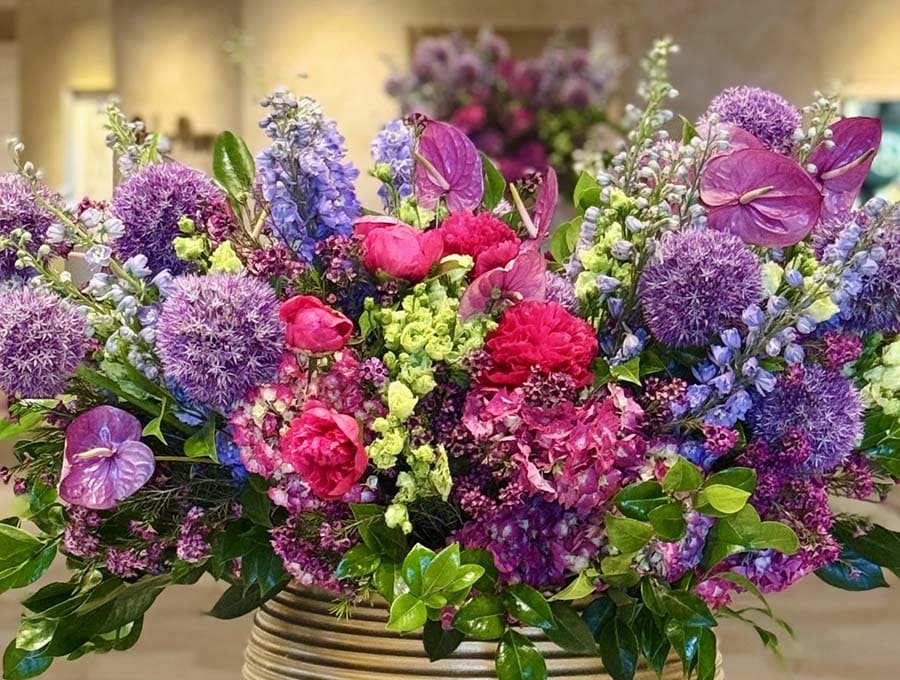 Colorful bouquet of flowers with pink, purple, and green colors in a woven basket.
