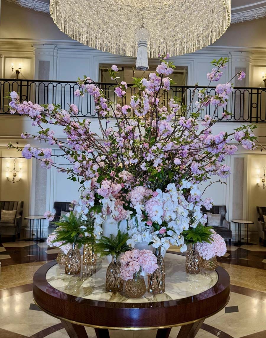 Large floral arrangement on a table in a grand hall with chandelier