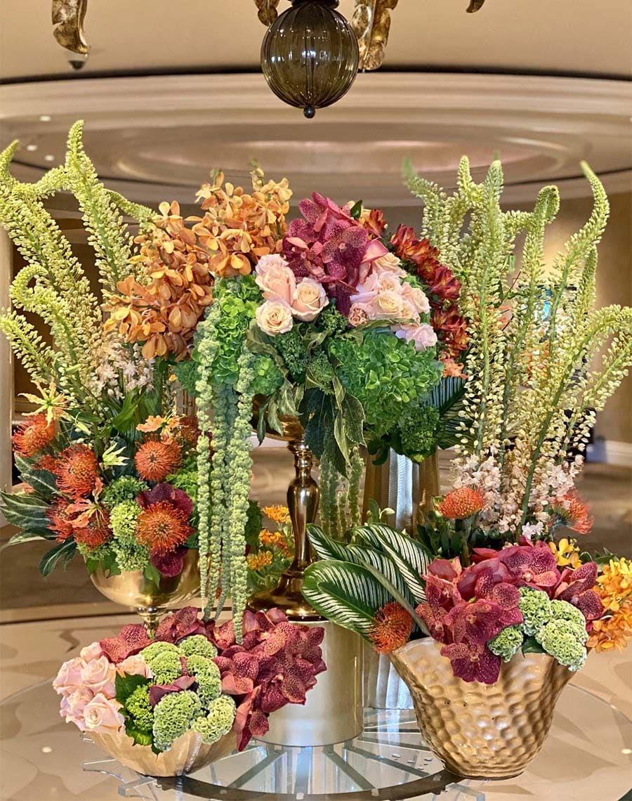 Decorative floral arrangements on a reflective surface with a blurred indoor background