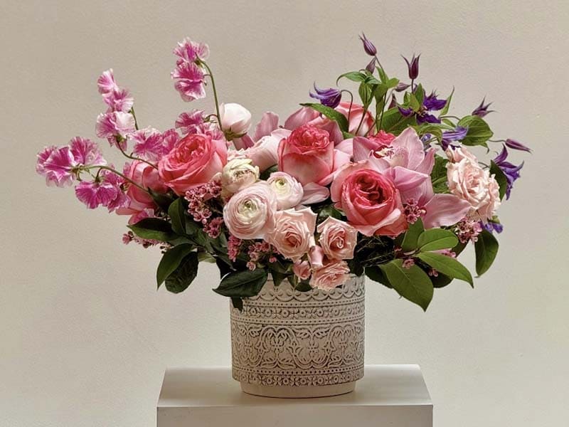 Bouquet of pink and white flowers in a decorative vase on a light background