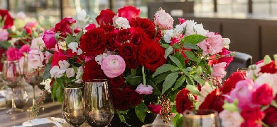 Elegant table setting with floral arrangements, candles, and gold cutlery on a white tablecloth.