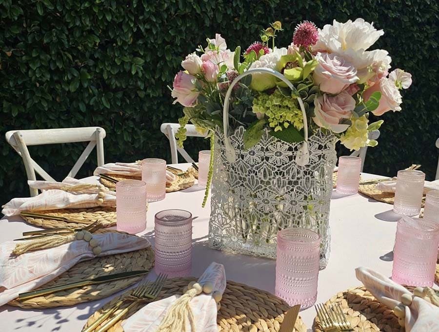 Decorative table setting with flowers, candles, and cutlery on a white tablecloth.