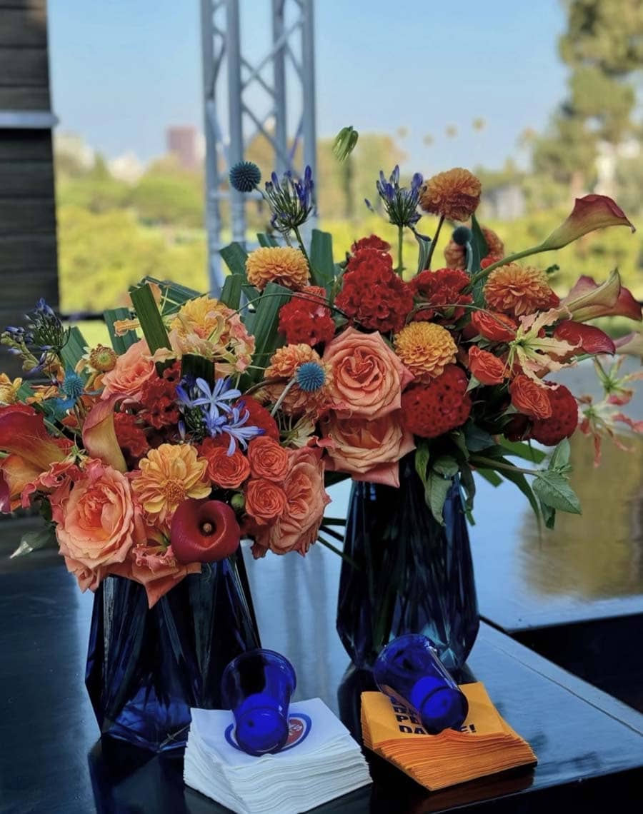 Colorful flower arrangements in black vases on a table with a blurred outdoor background