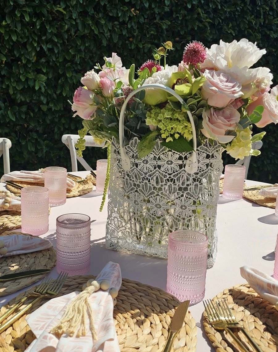 Decorative table setting with a lace lantern and floral arrangement outdoors.