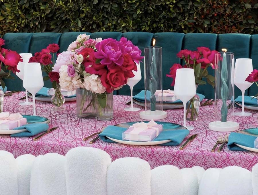 Decorative table setting with flowers, candles, and colorful tablecloth.