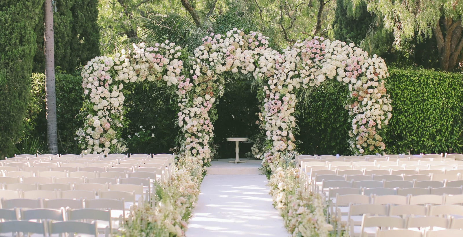Garden wedding ceremony with a full floral arch above the aisle