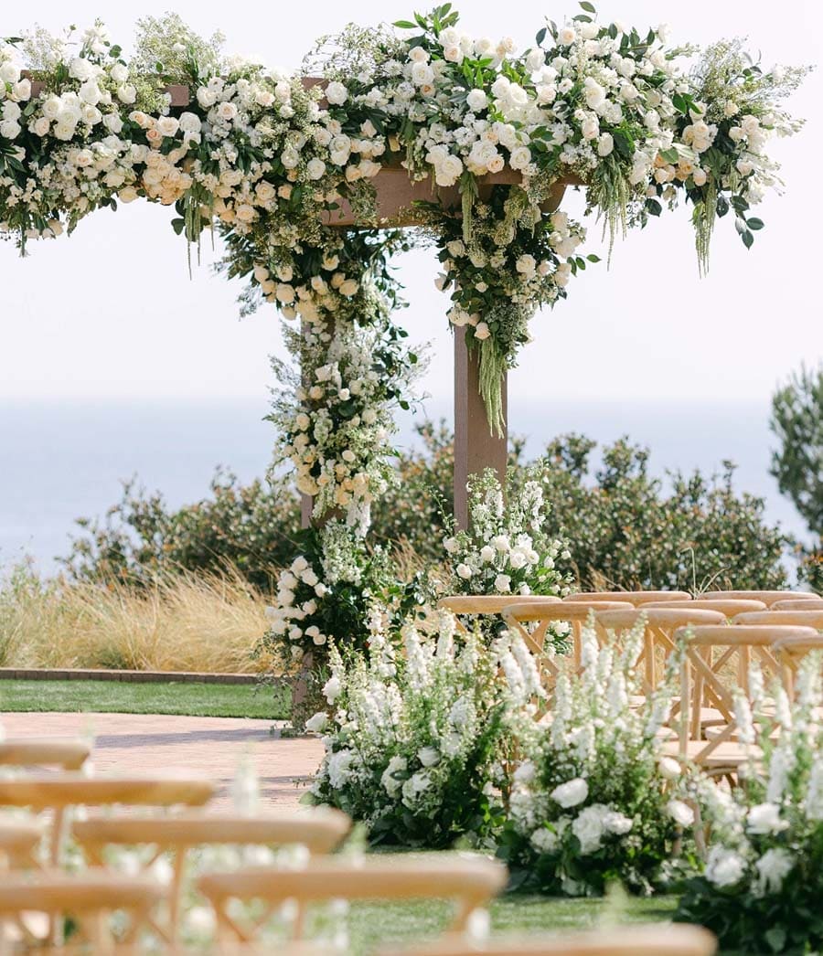 Decorative floral archway with white and green flowers at an outdoor event.