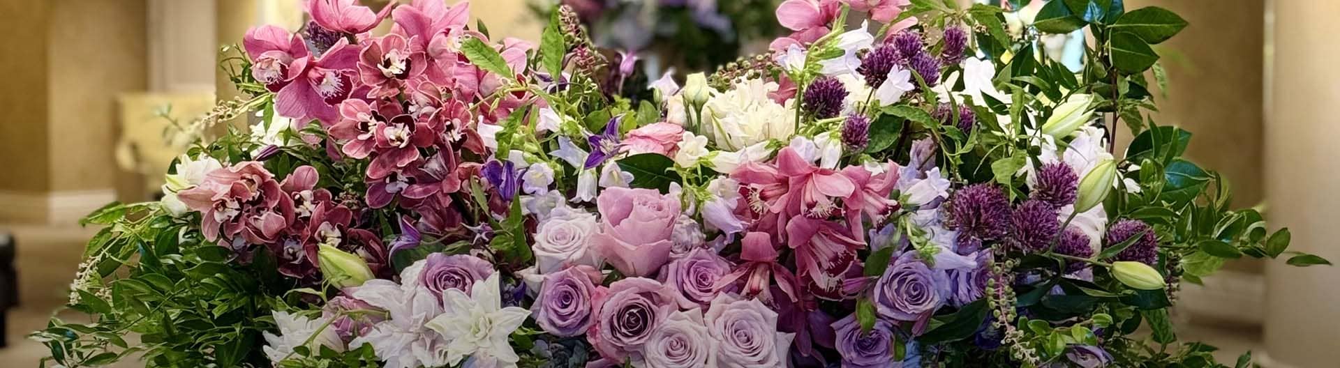 Bouquet of pink, purple, and white flowers with green leaves in a decorative setting.
