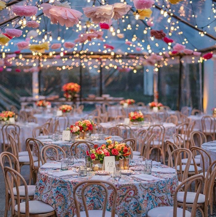 Decorated outdoor wedding reception with floral arrangements and string lights.