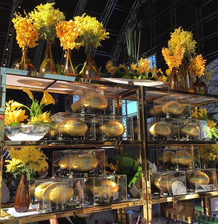 Display case with gold objects and yellow flowers in a large indoor setting
