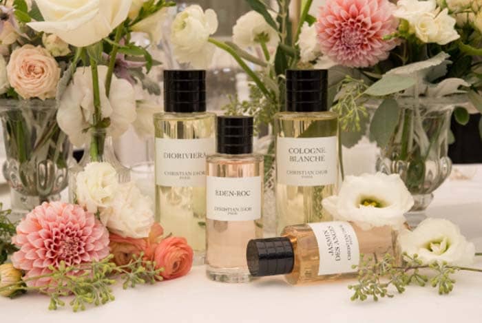 Perfume bottles on a table with flowers in the background
