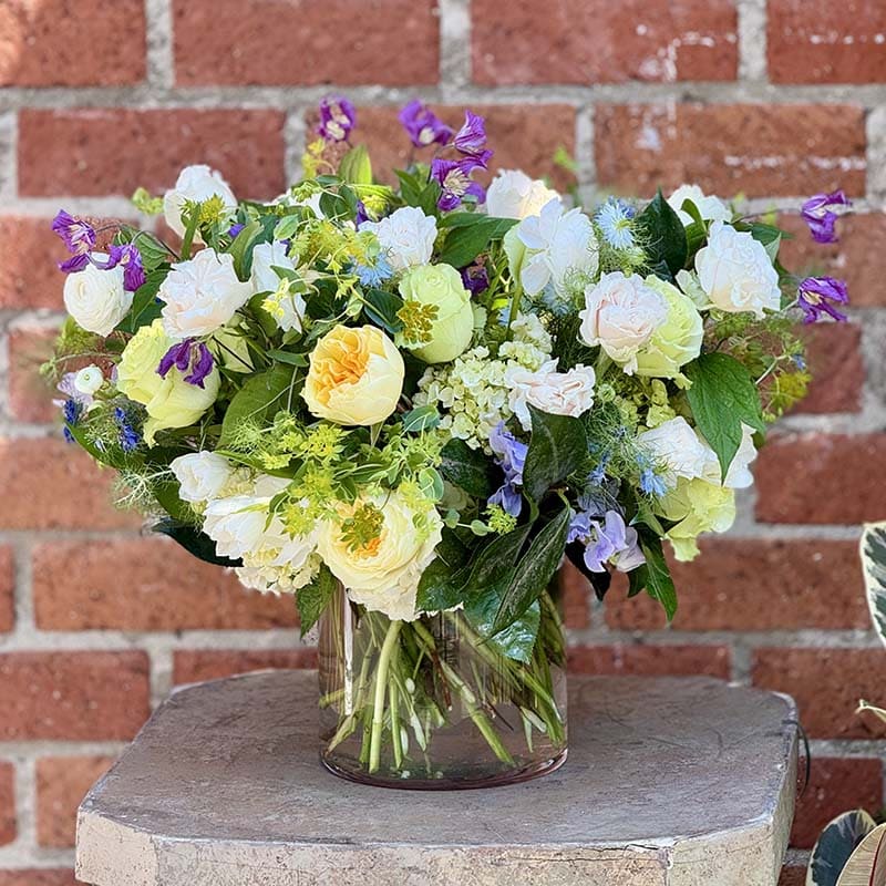 Bouquet of flowers in a clear vase against a brick wall