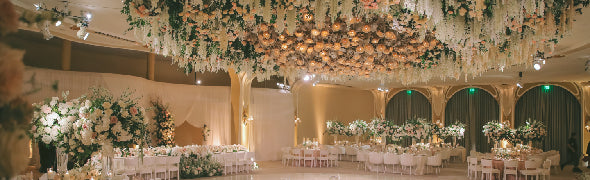 Outdoor dining setup under a wooden pergola with hanging lights and floral decorations.