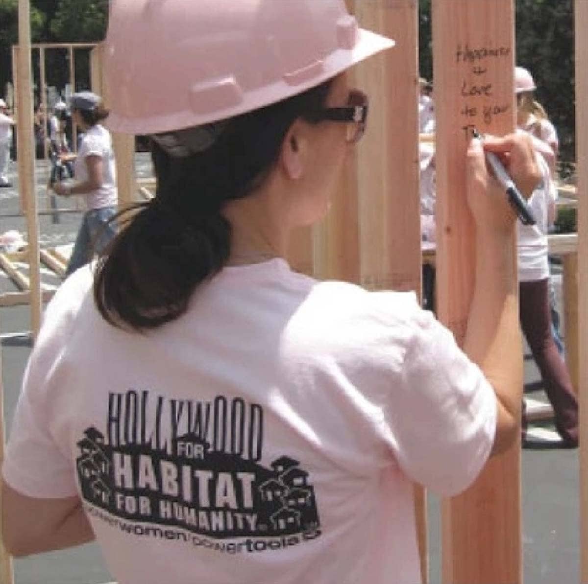 Person wearing a white t-shirt with 'Hollywood for Habitat for Humanity' on the back, working on a construction site.