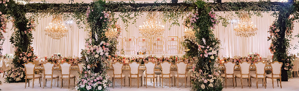 Decorated table with floral centerpieces and place settings outdoors.