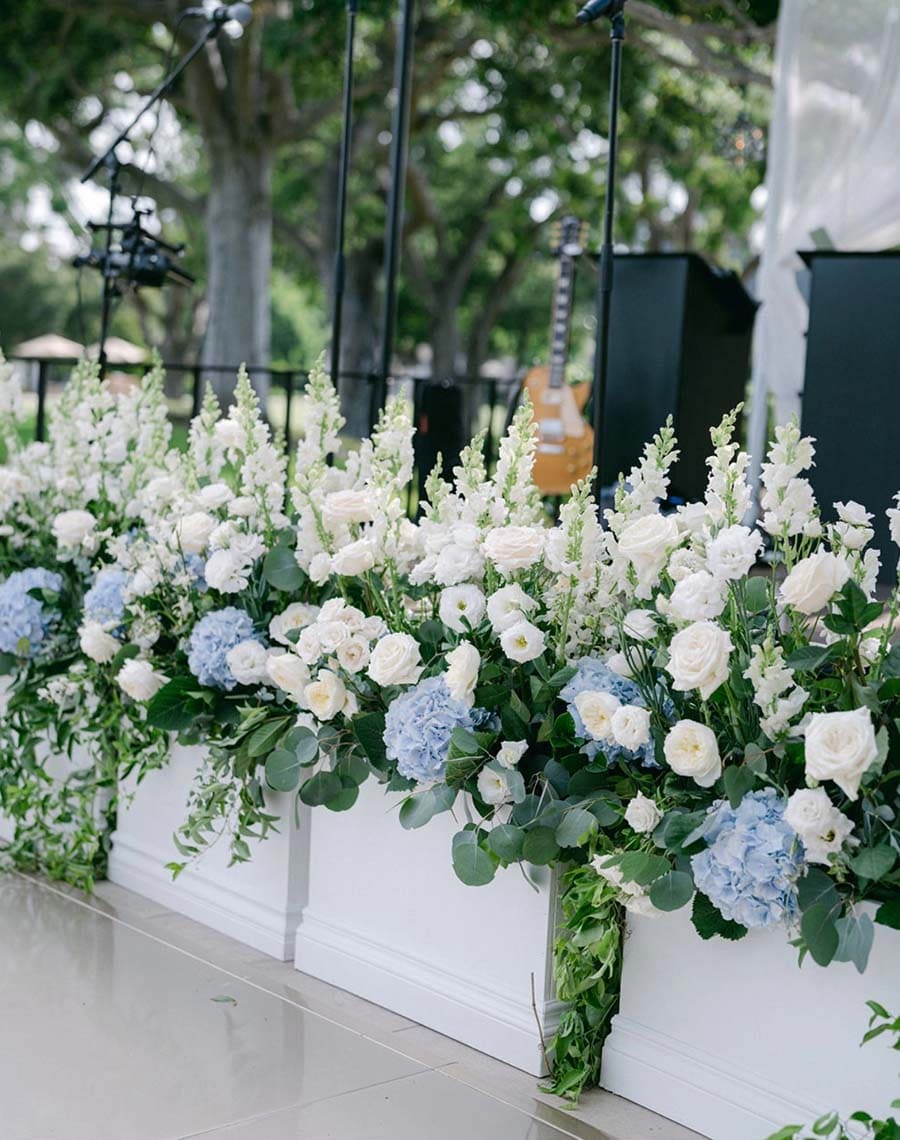 Decorative floral arrangement with white and blue flowers in white planters.