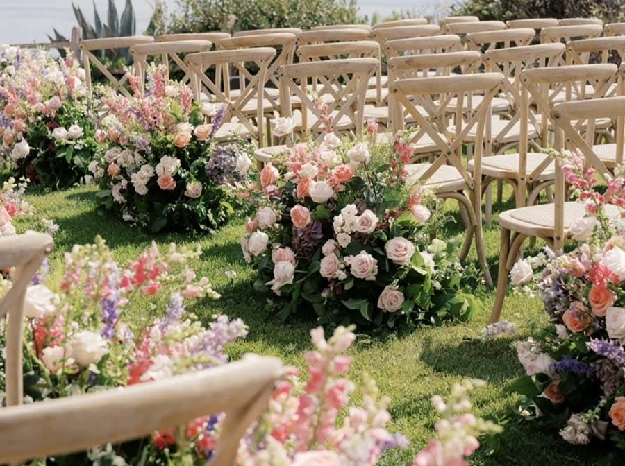 Decorative floral arrangements and chairs set up for an outdoor event.
